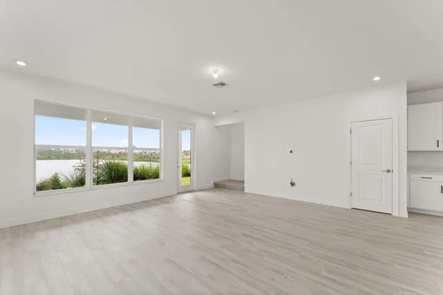 an empty room with wooden floor and windows