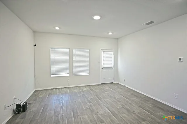 an empty room with wooden floor and windows