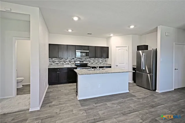 a large kitchen with a refrigerator and a stove top oven