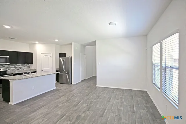 a large kitchen with stainless steel appliances a large counter top a stove a refrigerator and a window