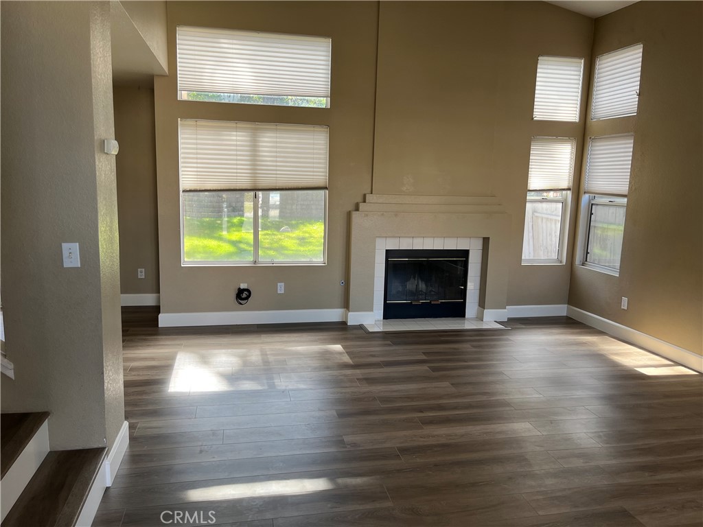 33033 Tulley Ranch Road Temecula, CA 92592 - Photo 2 of 14 an empty room with wooden floor fireplace and windows