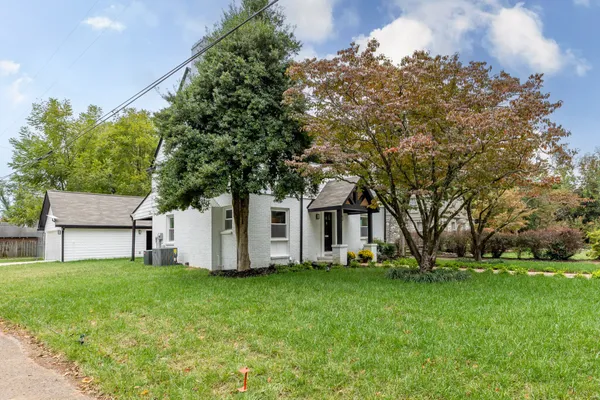 a big white house with a big yard and large trees