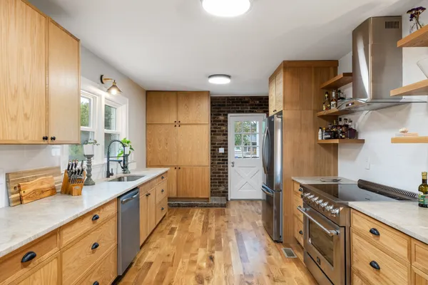 a kitchen with granite countertop a sink cabinets stainless steel appliances and a window