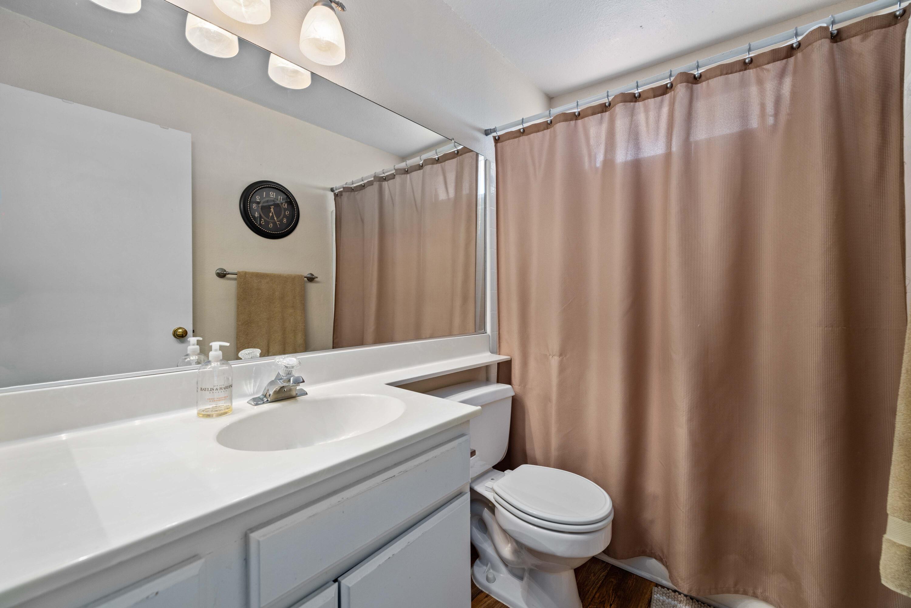 2833 Springfield Place Lancaster, CA 93536 - Photo 27 of 37 a bathroom with a sink a toilet and shower curtain
