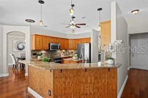 a kitchen with stainless steel appliances kitchen island granite countertop a stove a refrigerator a sink a dining table and chairs with wooden floor