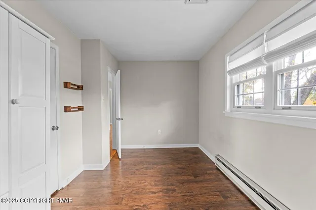 a view of empty room with wooden floor and kitchen view