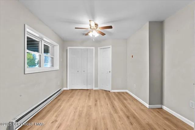 a view of empty room with wooden floor and fan