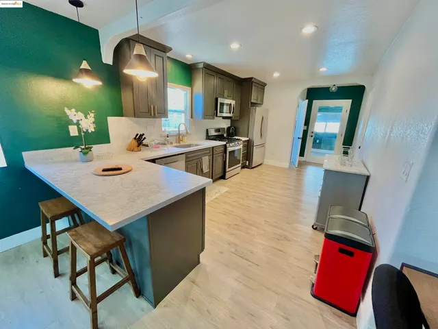 a kitchen with stainless steel appliances kitchen island granite countertop a table chairs and a refrigerator