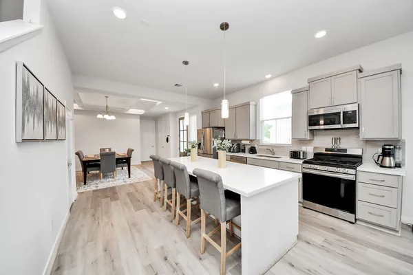 a kitchen with stainless steel appliances kitchen island granite countertop a stove top oven a sink dishwasher a dining table and chairs with wooden floor