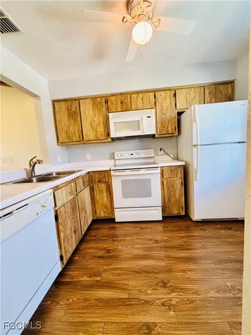 a view of an empty room with wooden floor and a ceiling fan
