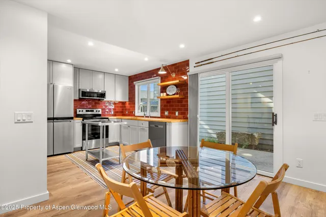 a kitchen with stainless steel appliances kitchen island granite countertop a refrigerator a stove a sink dishwasher with a dining table and chairs