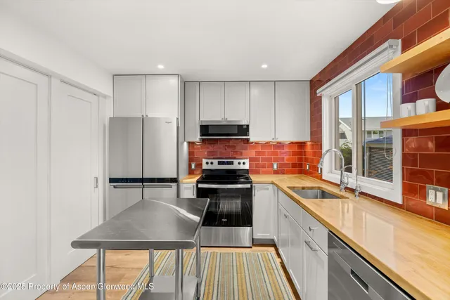 a kitchen with stainless steel appliances granite countertop a stove top oven a sink and a refrigerator