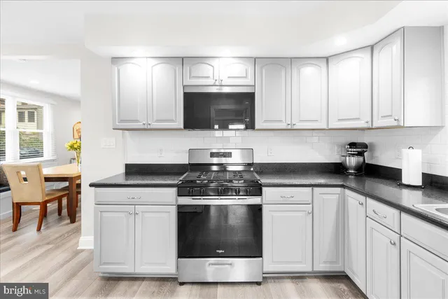 a kitchen with white cabinets and appliances