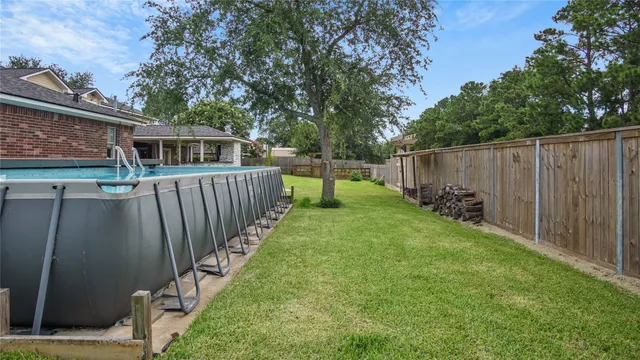 a view of a backyard with wooden fence and large trees