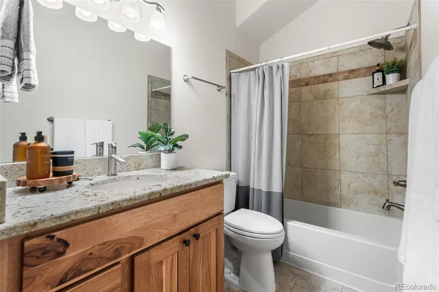 a bathroom with a granite countertop sink a toilet a mirror and bathtub