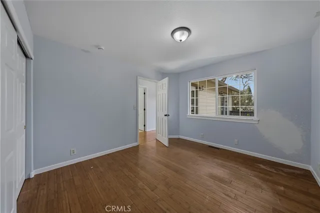 a view of an empty room with a window and wooden floor