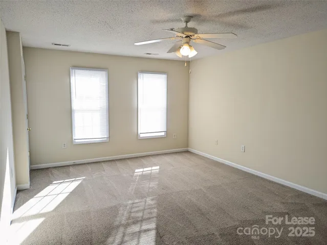 an empty room with windows and chandelier fan