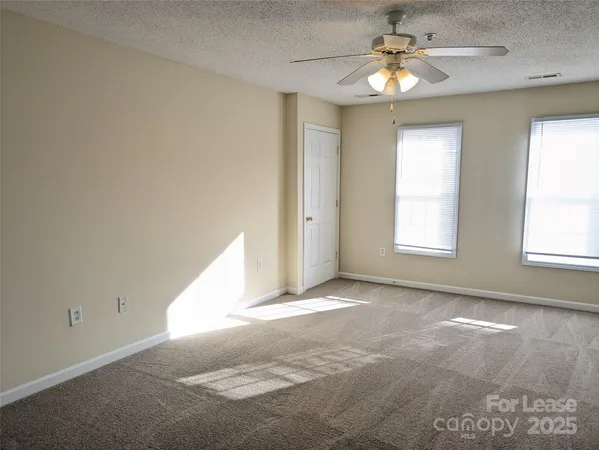 an empty room with windows and chandelier fan