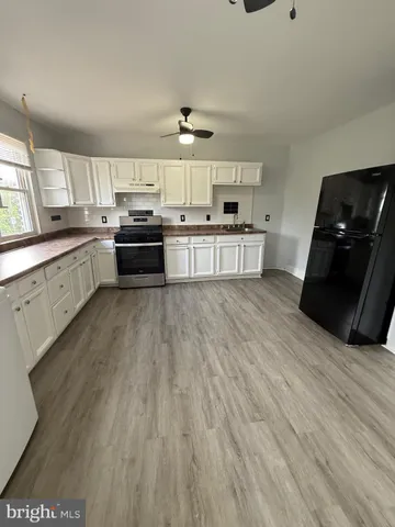 a kitchen with stainless steel appliances kitchen island granite countertop a sink cabinets and wooden floor