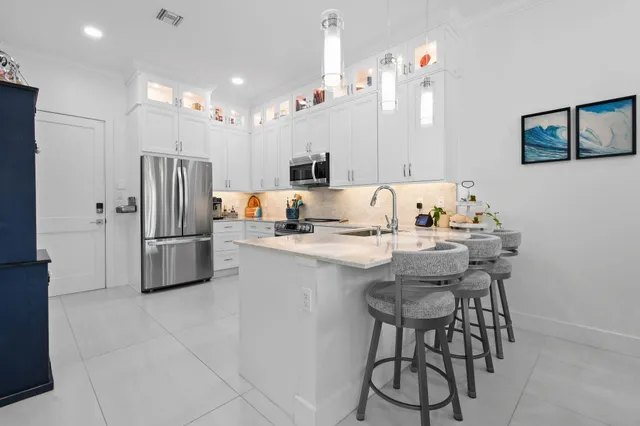 a large kitchen with stainless steel appliances kitchen island granite countertop a refrigerator and a sink
