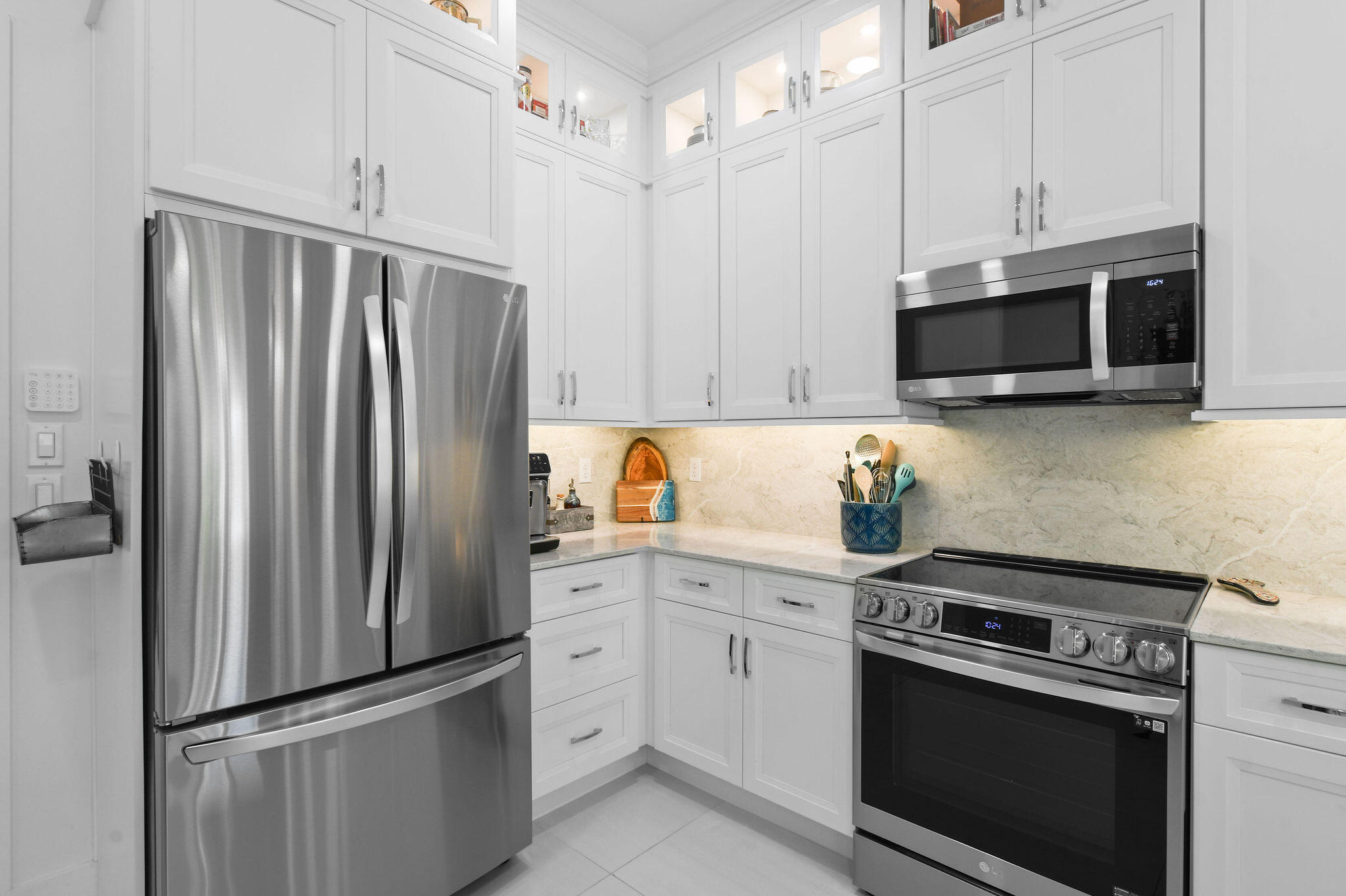 4707 Southeast Manatee Terrace Stuart, FL 34997 - Photo 10 of 68 a kitchen with stainless steel appliances white cabinets white stove a microwave and a refrigerator