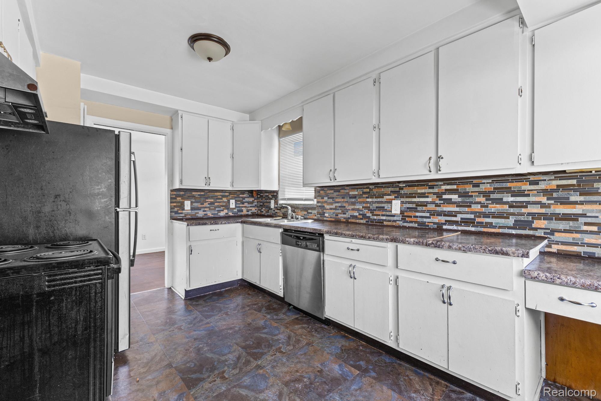 20261 Burt Road Detroit, MI 48219 - Photo 15 of 23 Kitchen featuring white cabinetry, a mosaic tile backsplash, dark countertops, and resilient flooring
