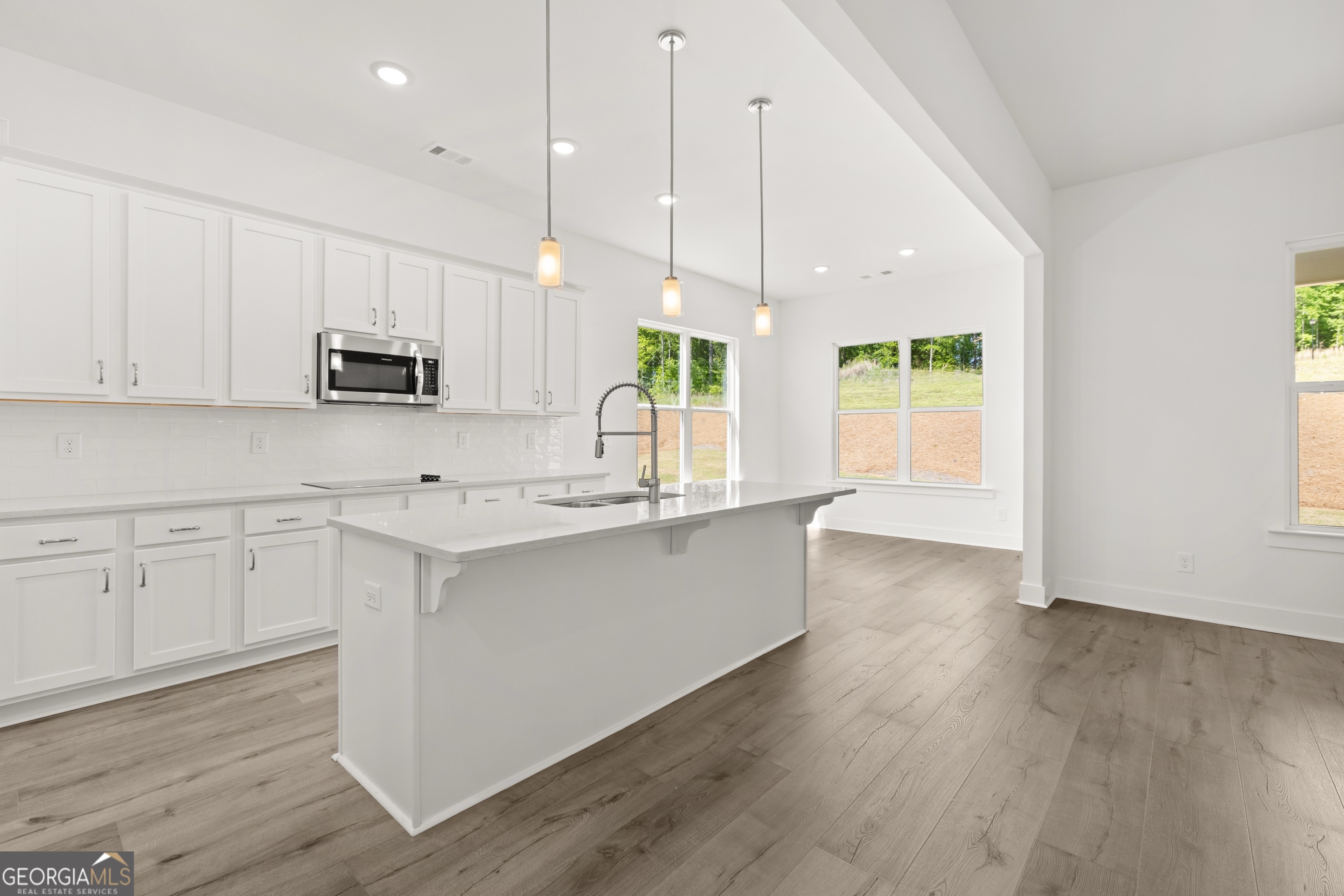 15 Overview Court Hoschton, GA 30548 - Photo 11 of 43 a kitchen with stainless steel appliances granite countertop a stove a sink a center island and a window
