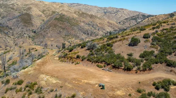 a view of a dry yard with mountains and green space