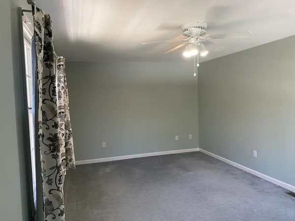 en empty room with window and chandelier fan