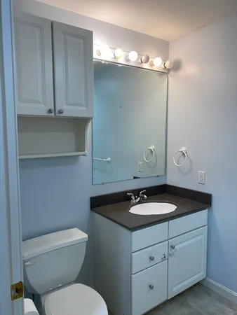 a bathroom with a granite countertop sink a toilet and vanity