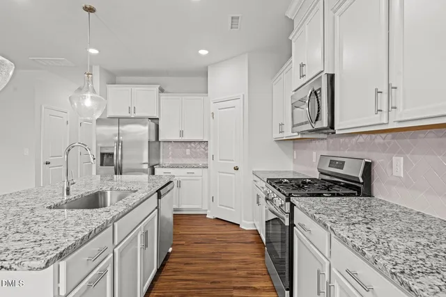 a kitchen with kitchen island granite countertop a sink cabinets a refrigerator and a stove
