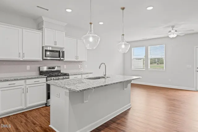 a kitchen with granite countertop white cabinets stainless steel appliances and wooden floor