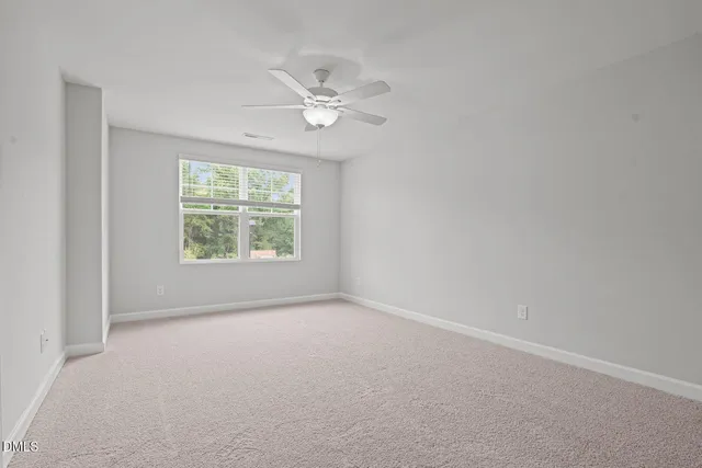 an empty room with windows and chandelier fan