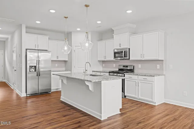 a kitchen with stainless steel appliances granite countertop a refrigerator a stove top oven a sink and dishwasher with wooden floor