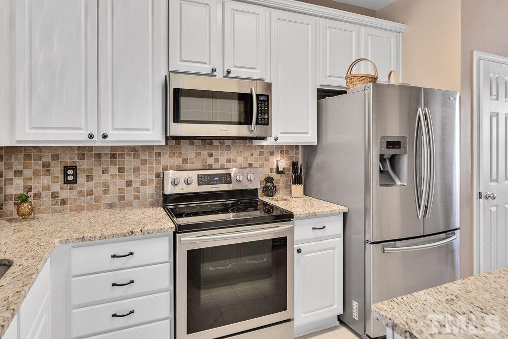 8348 City Loft Court Raleigh, NC 27613 - Photo 8 of 24 a kitchen with white cabinets and stainless steel appliances