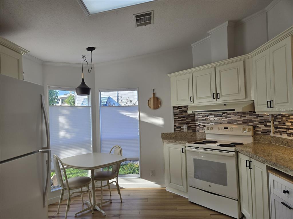 4146 Greenbluff Road, Unit 817 Zellwood, FL 32798 - Photo 16 of 40 a kitchen with stainless steel appliances a dining table chairs and white cabinets