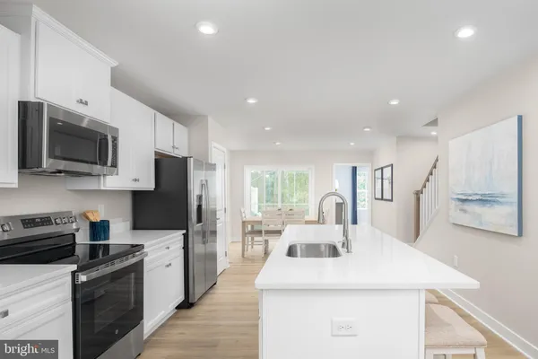 a kitchen with stainless steel appliances kitchen island granite countertop a sink a stove top oven a counter space and cabinets