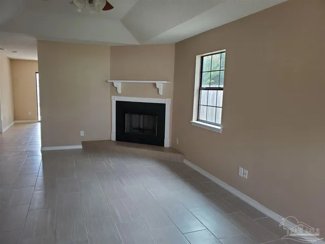 an empty room with windows and fireplace