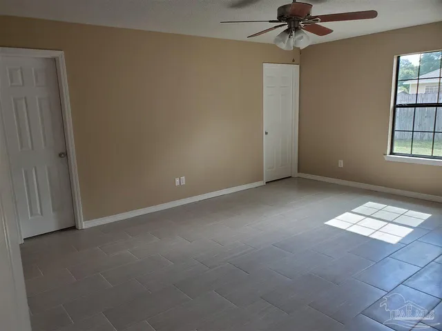 an empty room with windows and fan