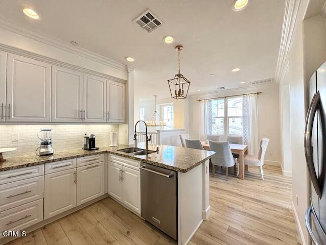 3640 Islander Walk Oxnard, CA 93035 - Photo 12 of 31 a kitchen with a sink dishwasher a stove a dining table and chairs with wooden floor