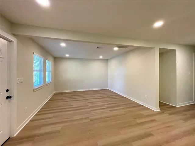 a view of empty room with wooden floor and window