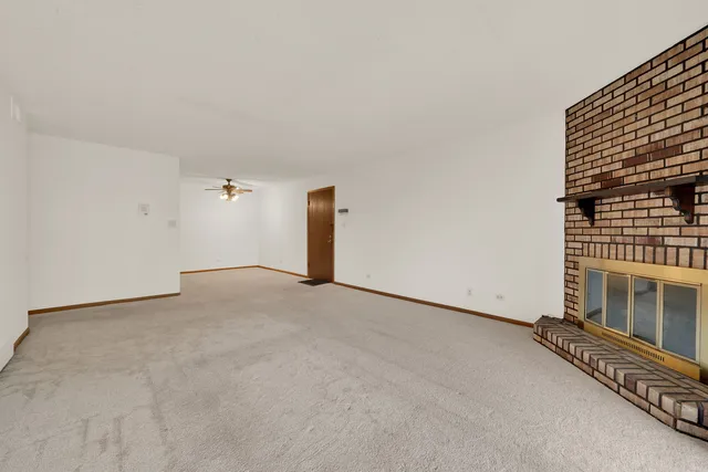a view of an empty room with wooden floor and a fireplace