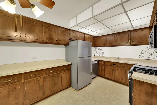 a kitchen with stainless steel appliances granite countertop a refrigerator a sink dishwasher a stove with wooden cabinets