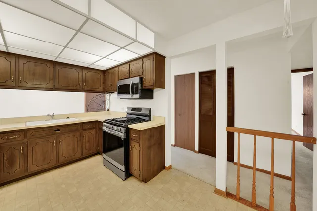 a kitchen with stainless steel appliances granite countertop a stove top oven a sink and a refrigerator