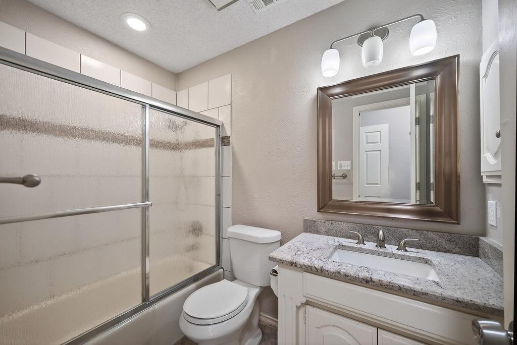 2229 Country Valley Road Garland, TX 75041 - Photo 13 of 34 a bathroom with a granite countertop sink toilet a mirror and shower