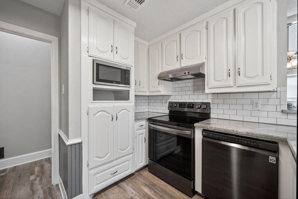 2229 Country Valley Road Garland, TX 75041 - Photo 19 of 34 a kitchen with stainless steel appliances granite countertop white cabinets and black appliances