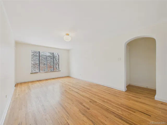 an empty room with wooden floor and window