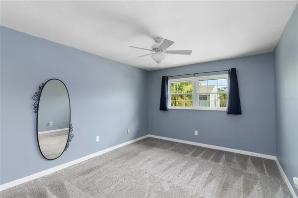 an empty room with windows and fan