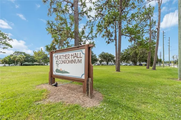 a view of a park that has a sign board large trees