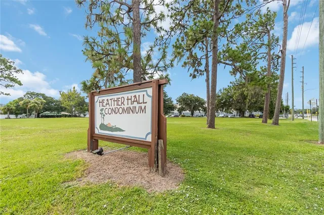 a view of a park that has a sign board large trees